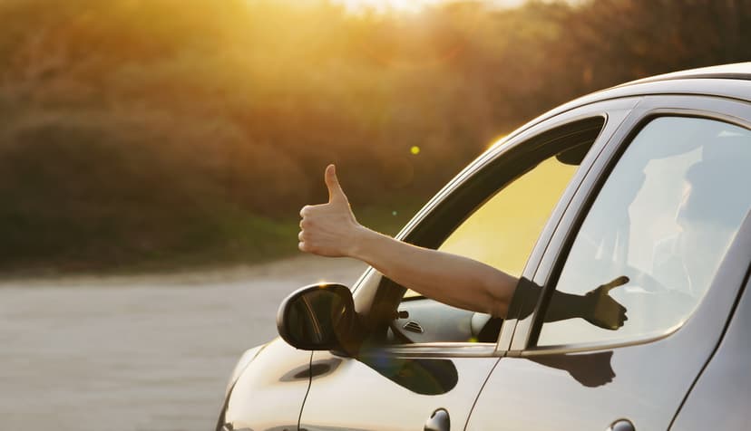 Persona en coche con mano afuera haciendo señal