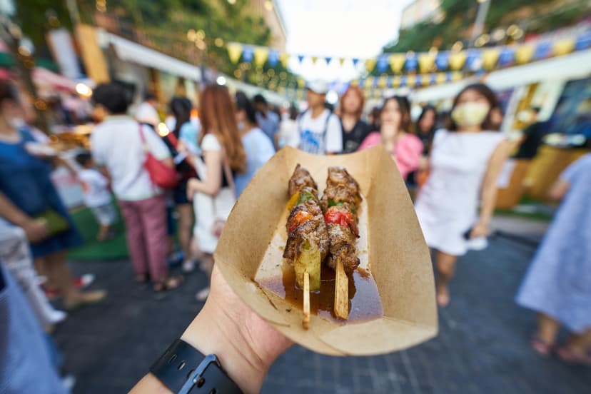 Persona degustando unas banderillas de carne en una feria gastronómica